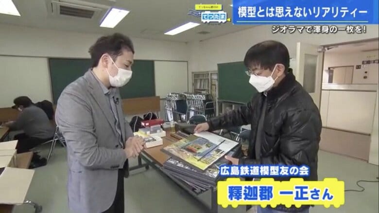 鉄道模型の写真パネルを見せてもらう野川アナ（左）