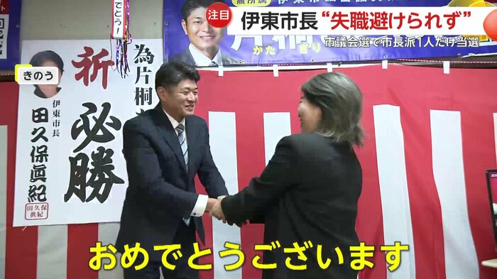 当選した候補を祝福する田久保市長(右)
