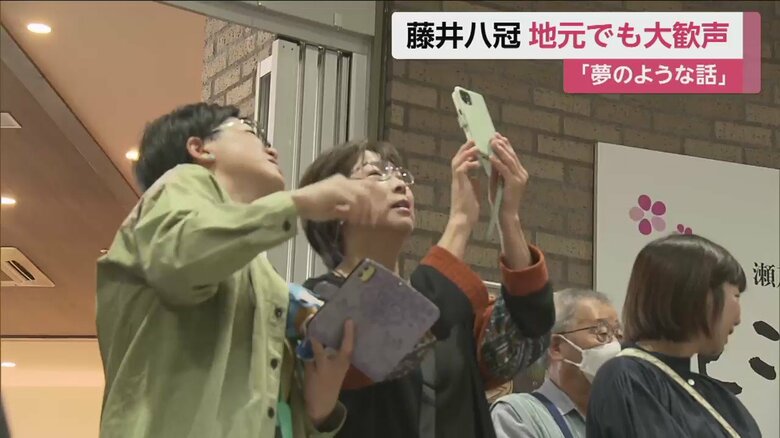 観光施設の垂れ幕を写真に収める人たち