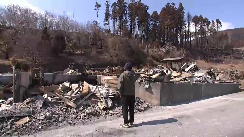 全焼した自宅跡を見つめ肩を落とす住民