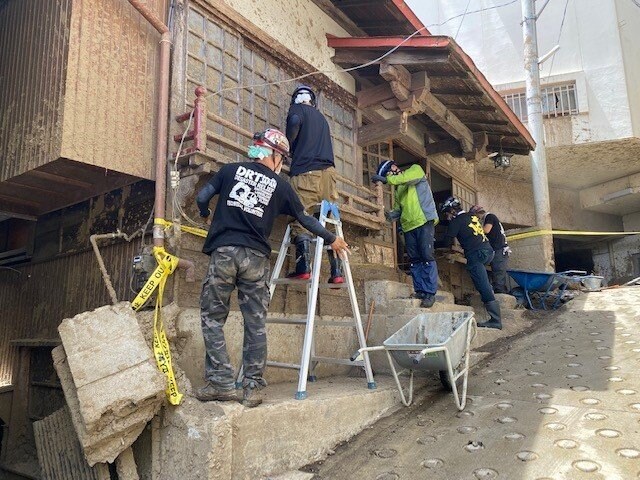 ボランティアが猛暑の中建物の復旧活動を行っている