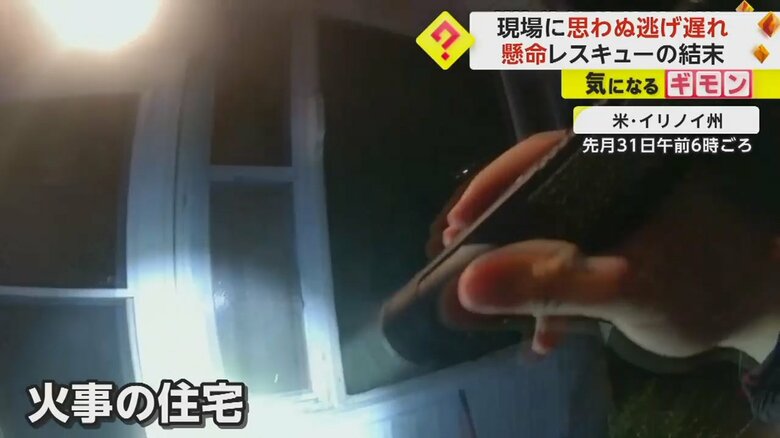 火災現場に駆けつけた警察官。ライトを扉に当てる