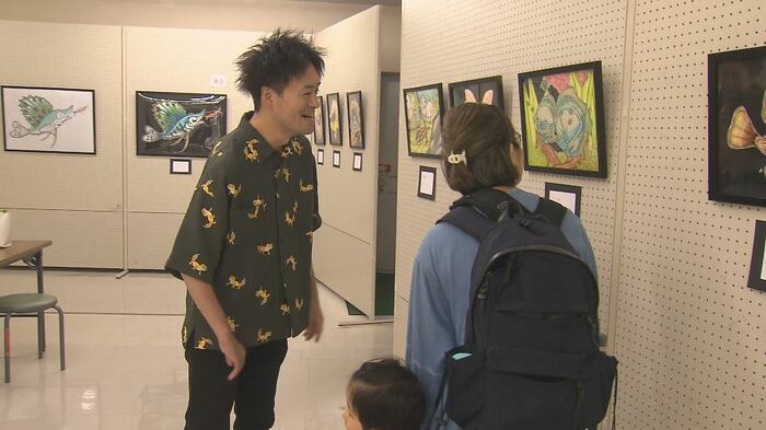 訪れた人に絵の説明をする新井さん
