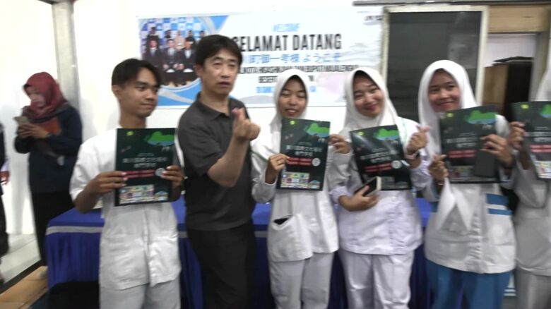 学生とポーズをとる富塚さん