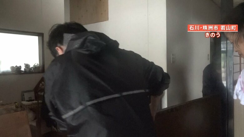 住人と協力して畳を運び出す取材スタッフ