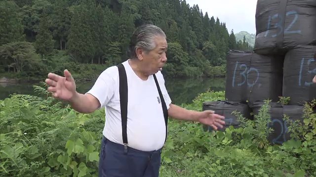 只見川沿いに積まれた土のうを前に　武藤勝弘さん（83）