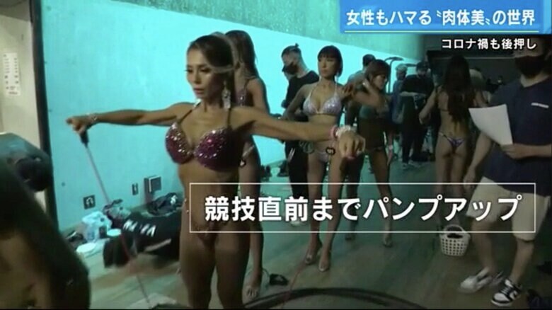 舞台裏でパンプアップして筋肉を調整する選手たち