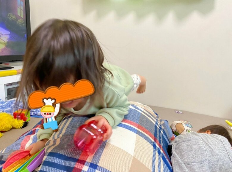 風船に布団をかけたお手製のおもちゃで遊ぶふたり