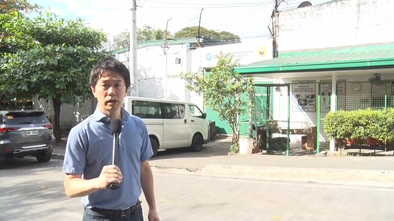 マニラのビクタン収容所前でリポートする筆者
