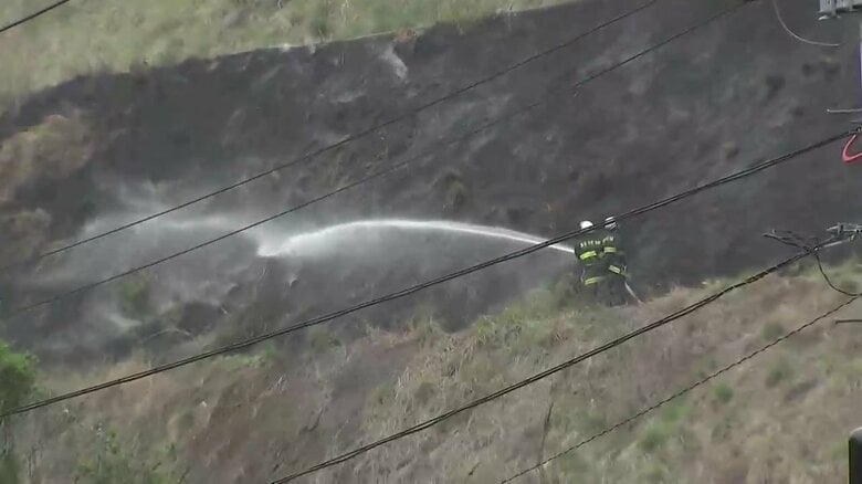 山の斜面で懸命の消火活動する消防隊員（4月27日午後2時ごろ）