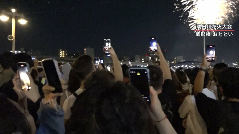 花火をスマートフォンで撮影する人々