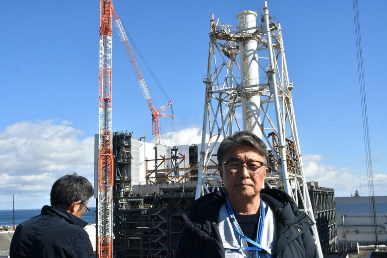 福島第一原発1号機と筆者（日本記者クラブの取材団に参加、原発敷地内の写真は代表撮影）