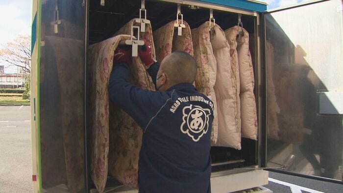 荷室の物干しざおに布団をかける作業