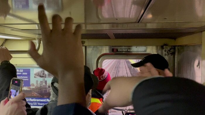 ホームの鉄道ファンに手を振る車内の鉄道ファン