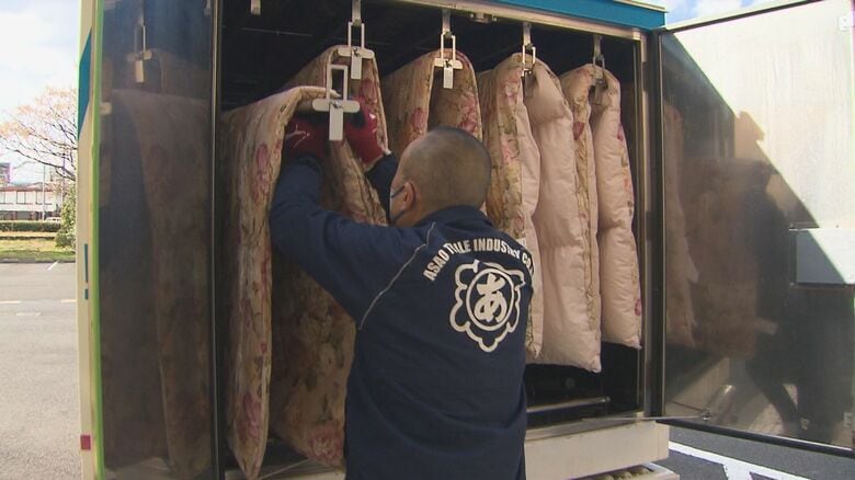 荷室の物干しざおに布団をかける作業