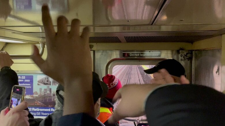 ホームの鉄道ファンに手を振る車内の鉄道ファン