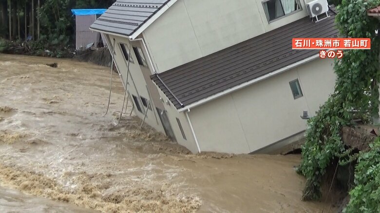 家が大きく傾き今にも川に流されそうになっている