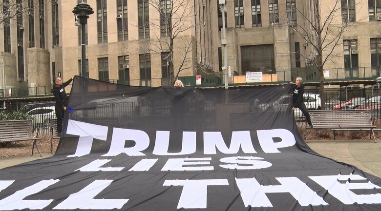 「トランプ氏は嘘つき」と書かれた巨大な垂れ幕で抗議する女性達