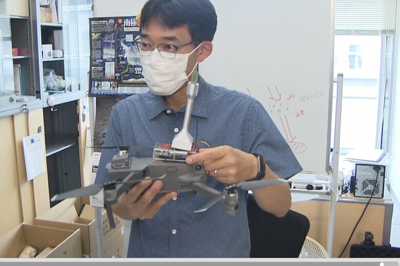 自作の観測装置をつけたドローンを手にする 極地研・猪上淳准教授
