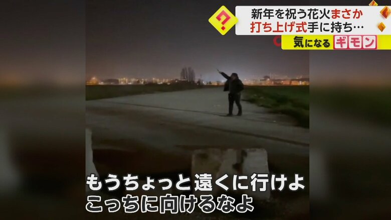 打ち上げ花火を手に持ち、夜空に向ける男性