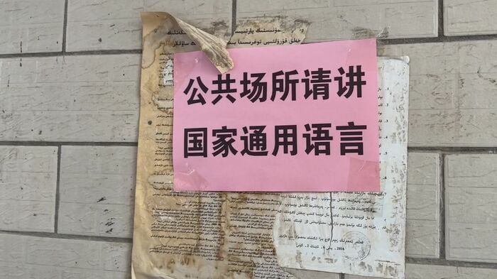 ウイグル語の張り紙の上には中国語で「公共の場では中国語を話すように」と注意書き