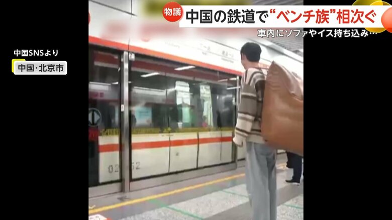 ホームから電車に乗り込む大きな荷物を背負った男性