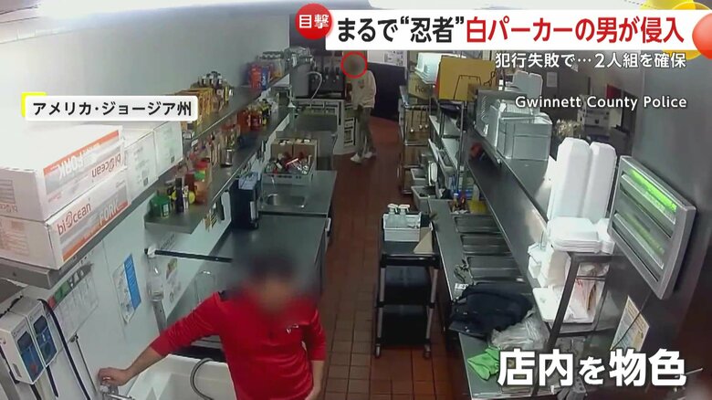 赤い服の店員の背後から接近する白いパーカーの男