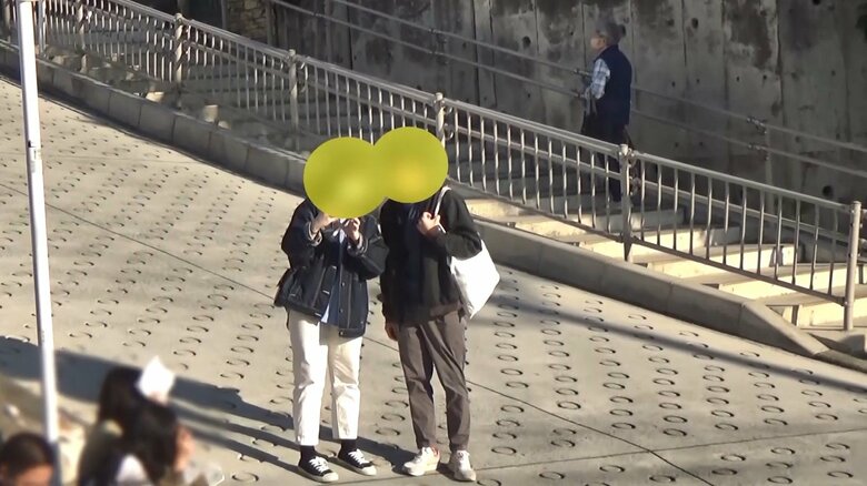 車道で写真撮影をする2人 後ろからクラクションが鳴る