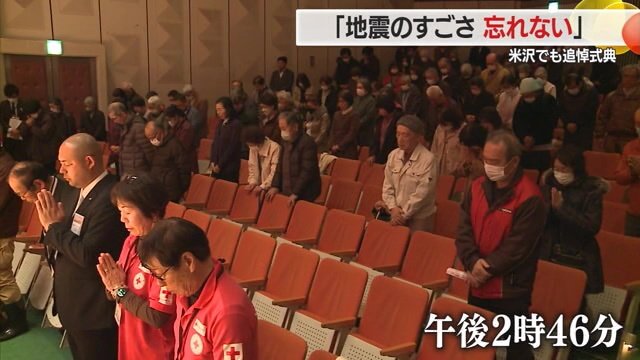 地震発生時刻に黙祷を捧げる人々