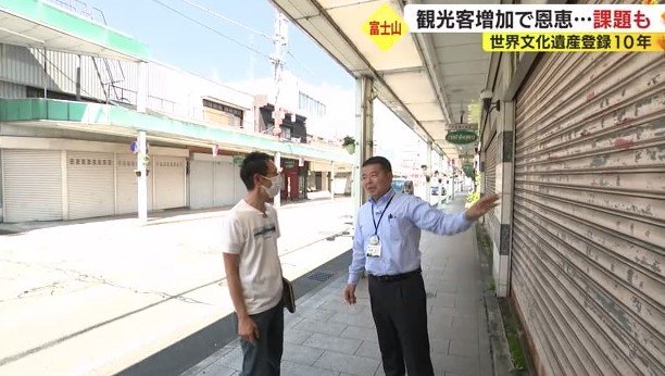 商店街を歩く記者(左)と富士宮市の伊藤課長(右)