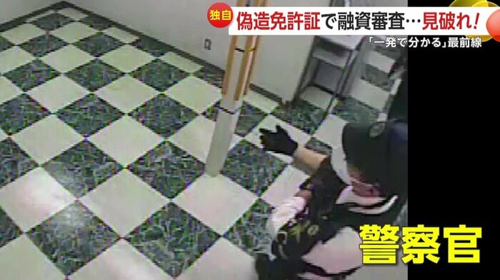 消費者金融の自動契約機がある部屋の外で女を待ち構える警察官