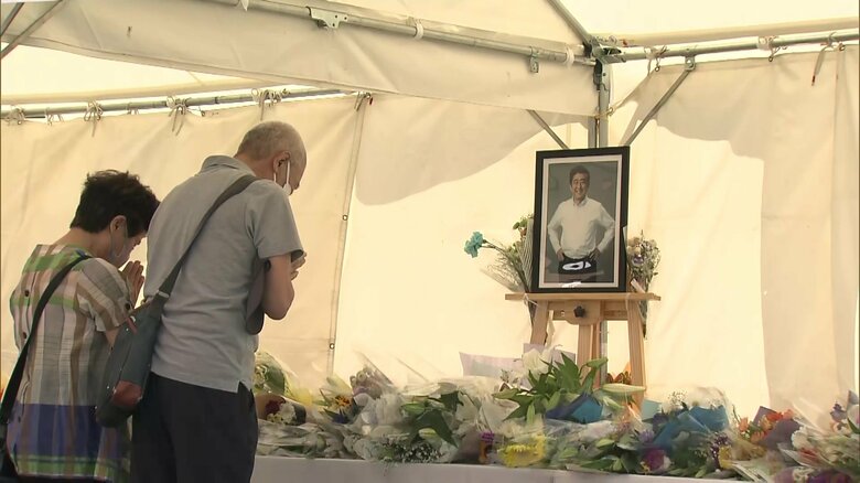 献花に訪れ手を合わせる人