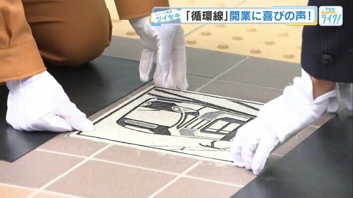 レリーフタイルを埋め込む沿線住民と工事関係者