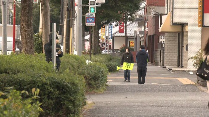 旗を持って子どもたちの登校を見守る地元住民