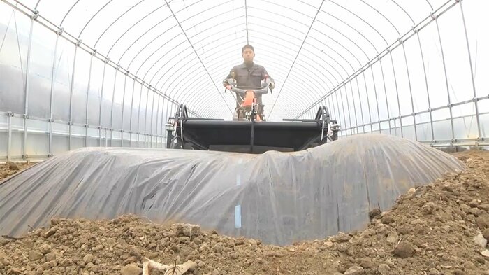 土にシートを張る機械を動かす様子