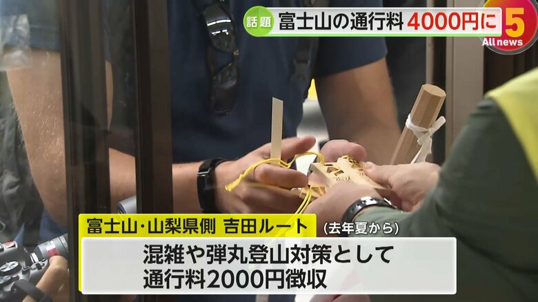 富士山の通行料を支払い記念の木札を受け取る人