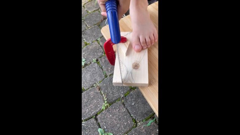 制作の様子　木材をのこぎりで切っている