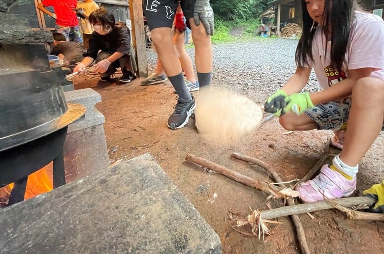薪を割って火を起こし、大きなかまどでご飯を炊く