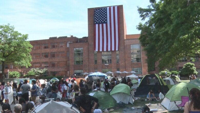 抗議デモに反対する人達が星条旗を校舎に吊した