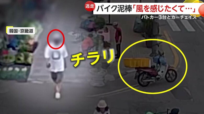バイクをチラリと見た白いシャツの男