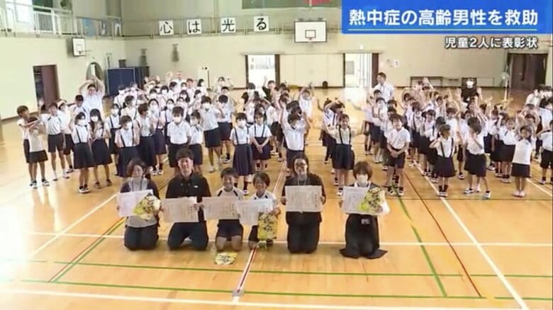 中条小学校のみんなの前で表彰された松岡くんと杉野くん、教職員たち