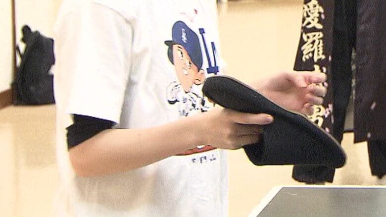 ラケットではなくスリッパを手に