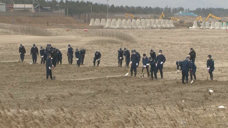 骨が見つかった砂浜を捜索する捜査員