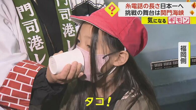 「タコ！」と糸電話に向かって話す小学生