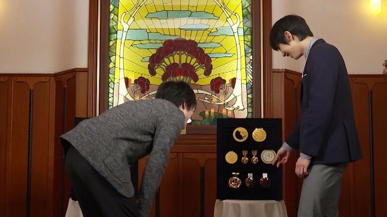 羽生結弦のメダルを見ている内村航平（左）