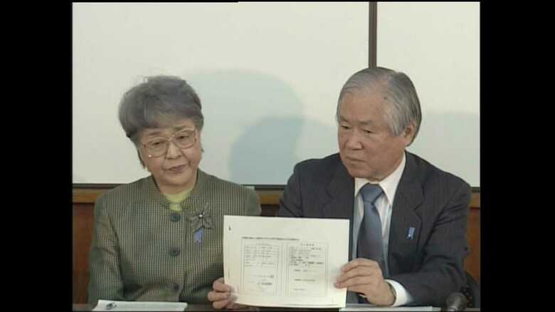 死亡確認書を見せながら会見をする横田夫妻