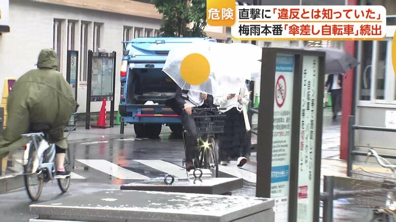 傘を差しながら自転車で進む人