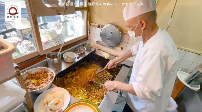 長いヘラを使って焼きそばを焼く