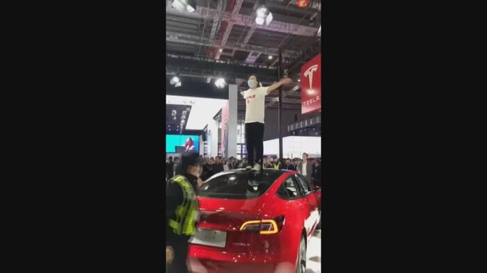 モーターショー会場でテスラ車によじ登る女性(ウェイボより)