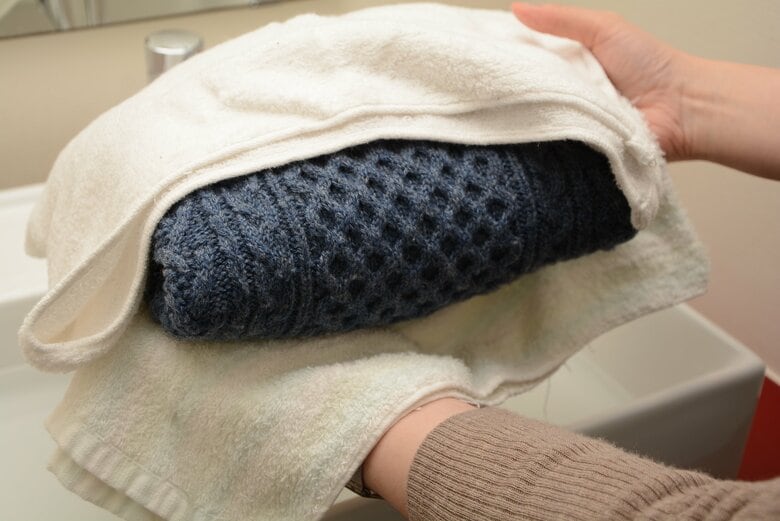手洗いでの押し洗いの流れ。ニット類をサンドイッチするように2枚のタオルで挟む